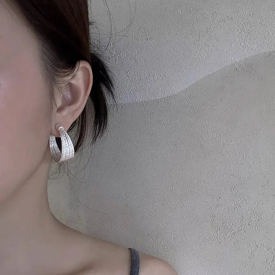 Set of four geometric earring pairs in silver and gold, including stud and clip styles