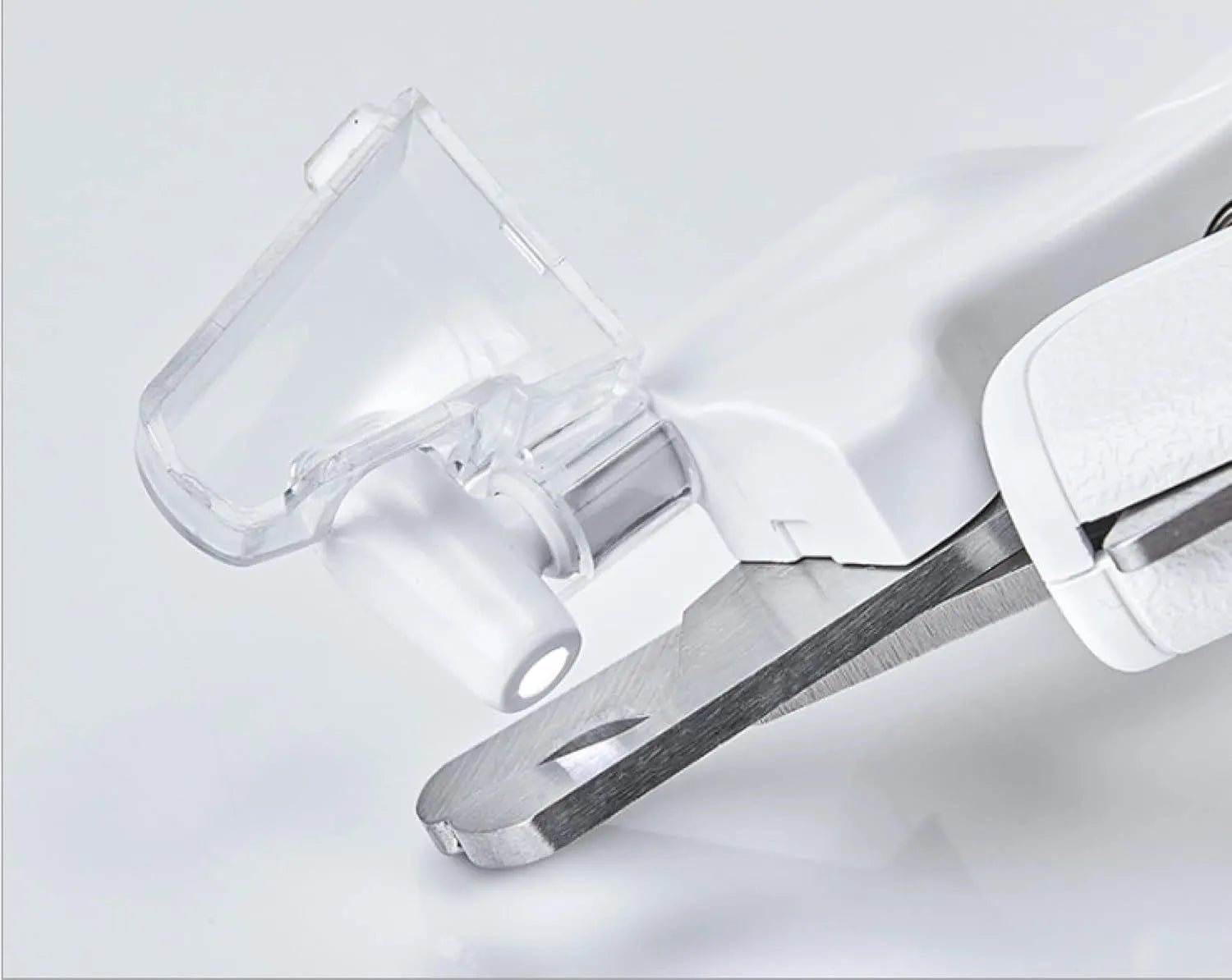 White pet nail clippers with LED light, transparent guard, and nail file on a grey background.