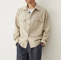 Men's light sand rice coloured casual shirt with simple lapel and long sleeves on a hanger.