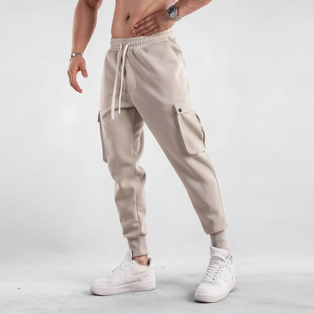 Men's loose-fit cotton sports trousers with ankle-tied cuffs and multiple pockets in a light grey colour.
