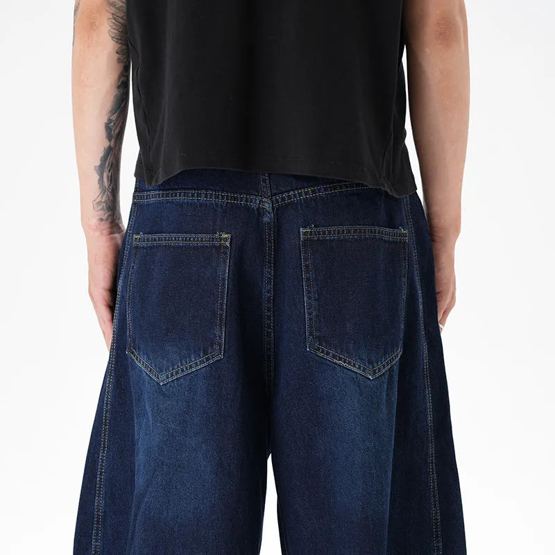 Dark blue washed distressed wide leg machete jeans showing fading and whiskering details