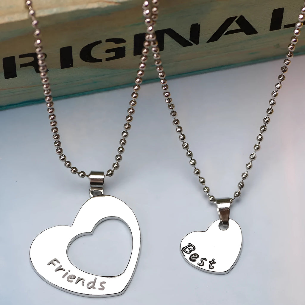 Two matching silver heart-shaped cross chain necklaces on a surface, alloy construction
