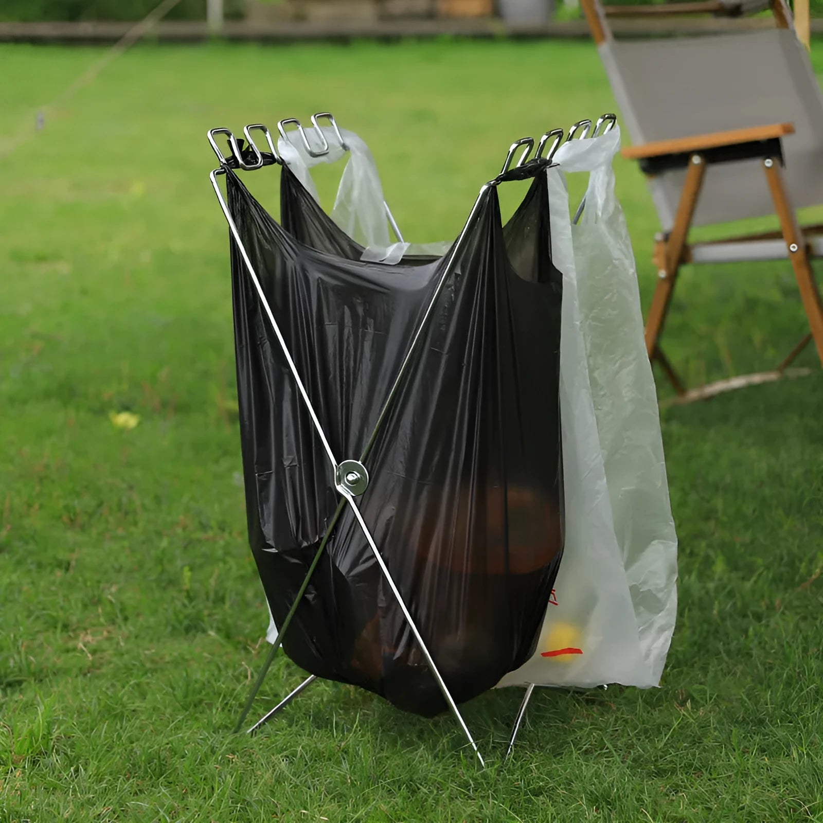 Silver folding stainless steel garbage bag holder bracket on a wooden surface.