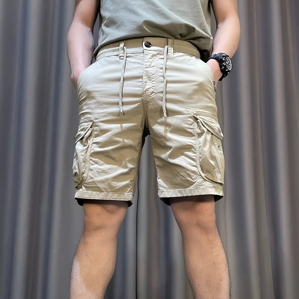 A pair of loose-fitting, straight-leg multi-pocket overalls trousers in a khaki colour on a model.