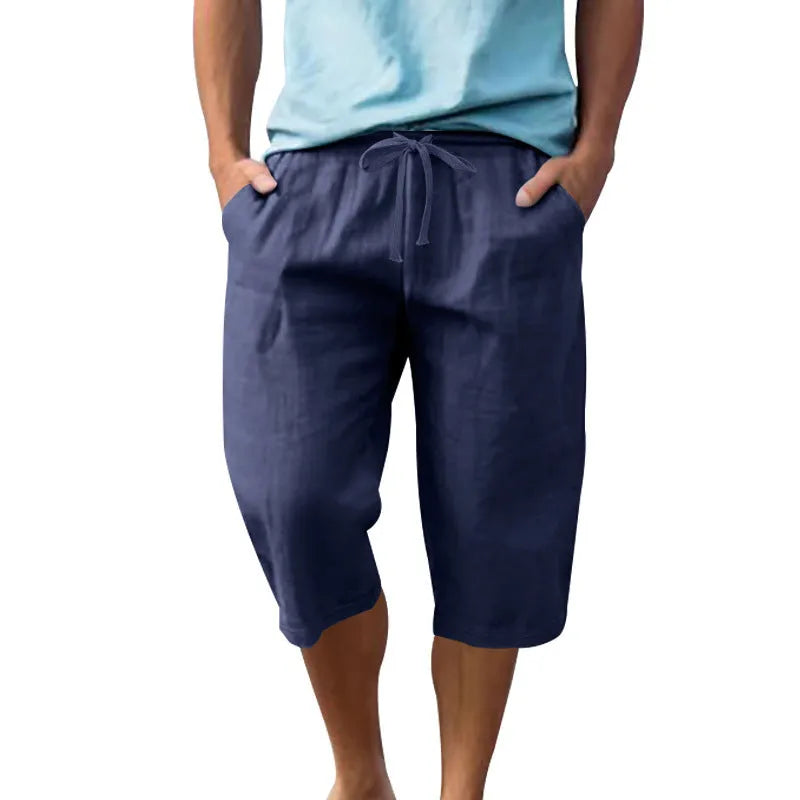 Man wearing loose, cropped linen shorts in a solid colour with a drawstring waist.