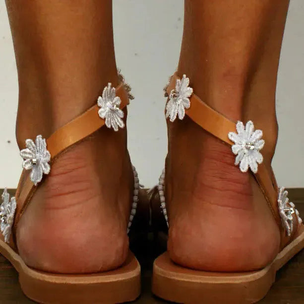 Brown ladies' Roman sandals with floral pattern and herringbone toe detail on a flat rubber sole.