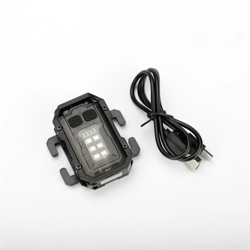 Black portable tactical mini warning flashlight with USB charging cable on a backpack strap.