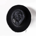 Handmade wool felt hat with conical crown and skull embroidery on a denim base.