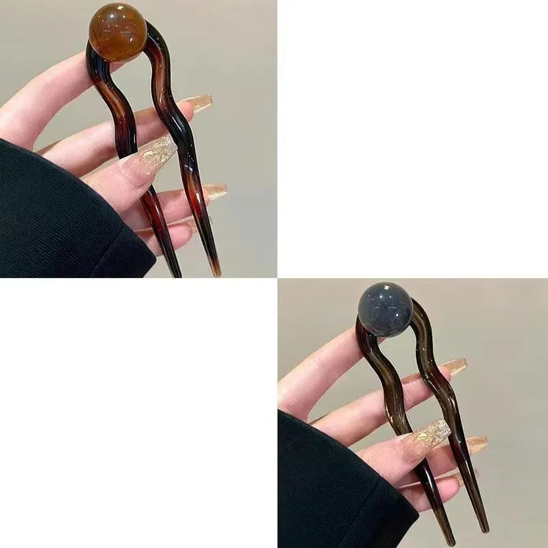 A set of simple U-shaped acrylic hair barrettes with a retro ball detail in beige and caramel colours.