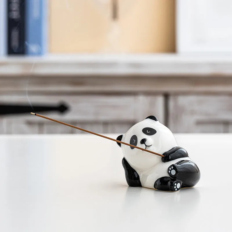 Ceramic panda incense holder in squinting style on a desk, 8.5cm high, with a lit incense stick