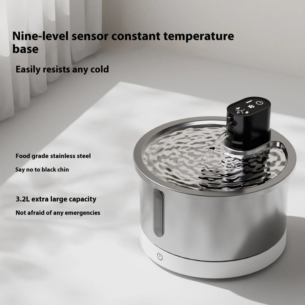 Stainless steel heated pet water fountain on a white base with a charging cable.