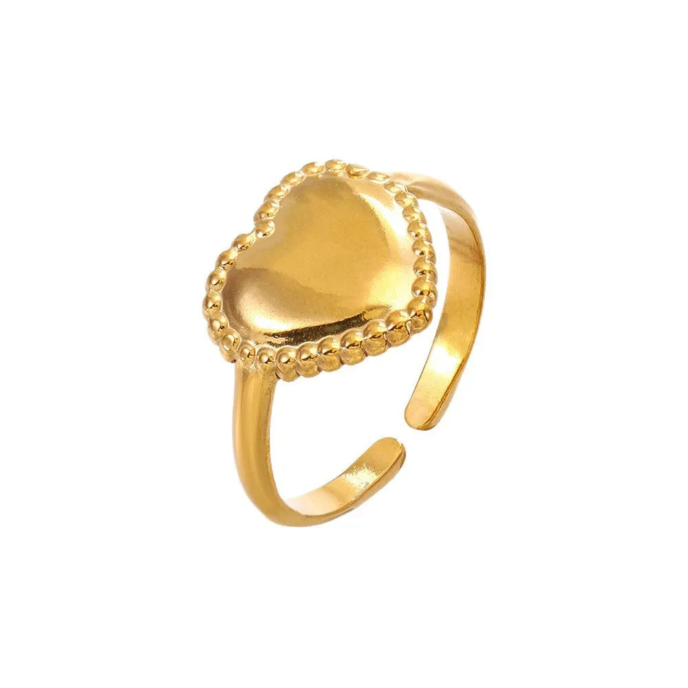 Adjustable stainless steel heart ring with electroplated gold finish on plain background