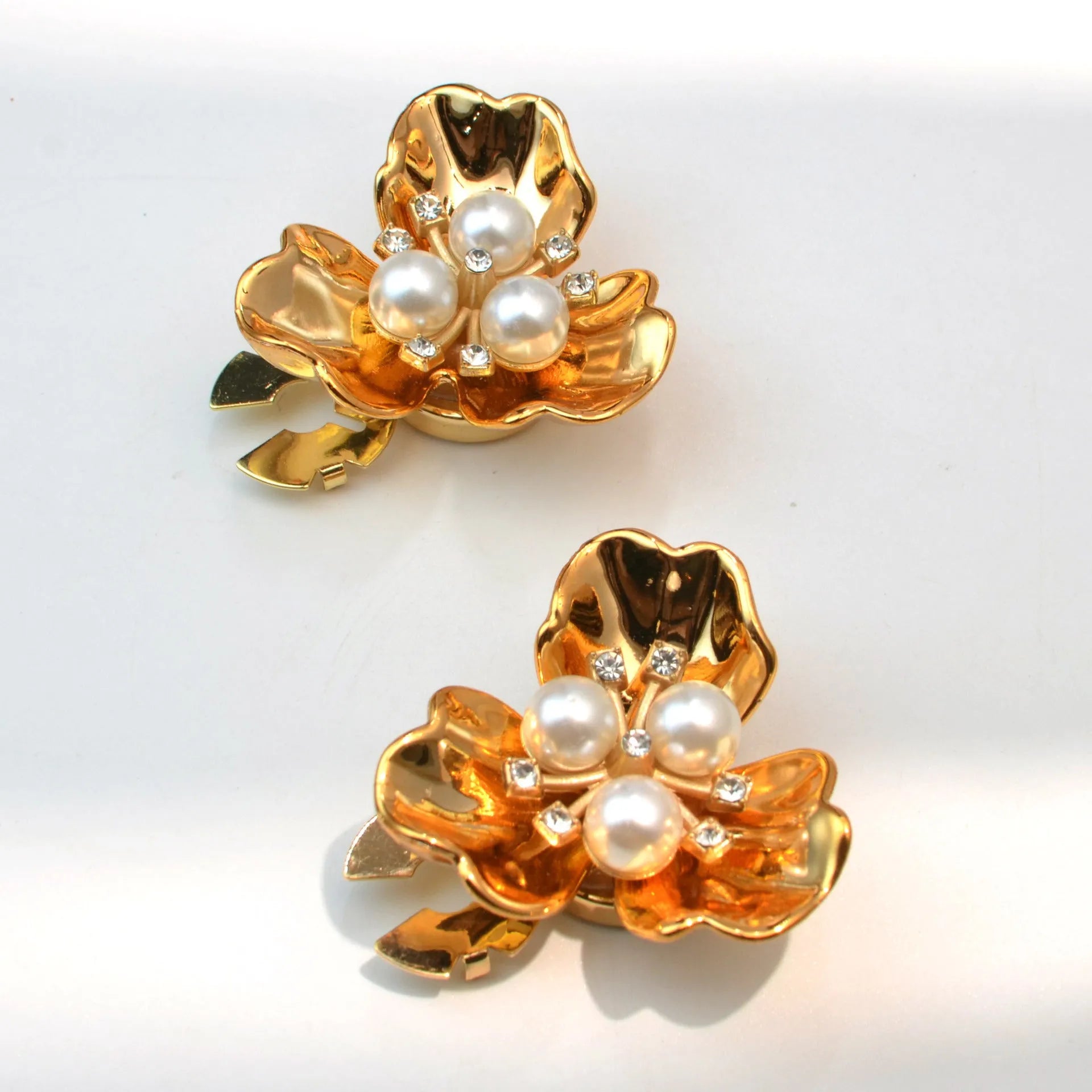 Metal cufflinks with pearl three-flap design in gold, pink, red, and white colours on white background