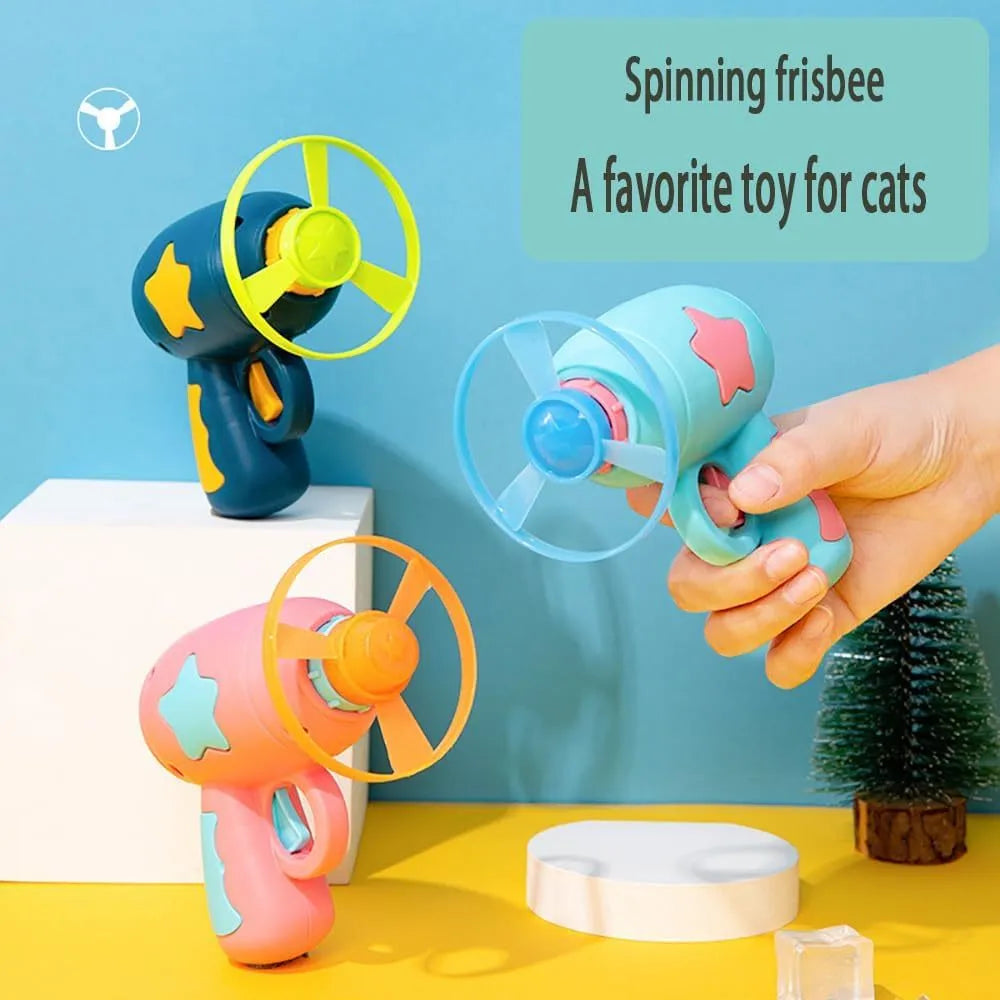 Blue interactive cat toy gun with a plastic frisbee on the launch head, shown next to a second pink frisbee.