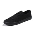 All-black low-top women's canvas shoes with flat rubber sole and lace-up front