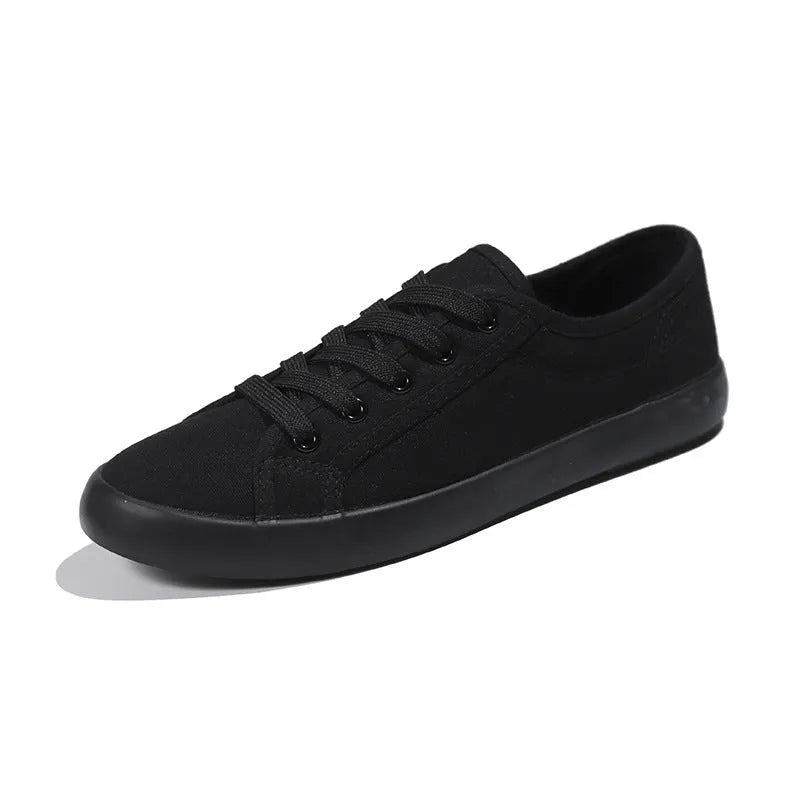 All-black low-top women's canvas shoes with flat rubber sole and lace-up front