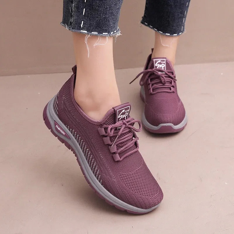 Women's black mesh sneakers with round toe and cross strap detail on rubber sole