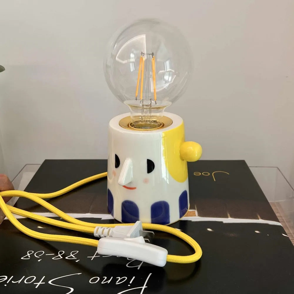 Handmade ceramic bedside lamp with a creative ball headlight design on a wooden table.