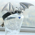 Black patent leather choker collar with detachable red devil wings and a small metal bell attached.