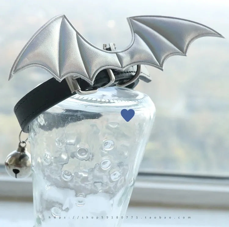 Black patent leather choker collar with detachable red devil wings and a small metal bell attached.