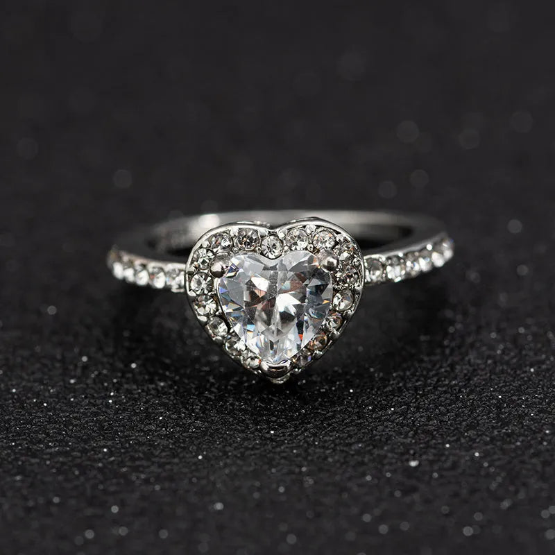 Women's heart-shaped wedding ring with central crystal on white copper band in rose gold finish.