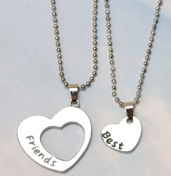 Two matching silver heart-shaped cross chain necklaces on a surface, alloy construction