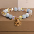 Women's aquamarine crystal bracelet with a four-leaf clover charm and small pearl accent.