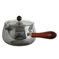 Transparent rotary glass teapot with wooden handle and built-in infuser on countertop