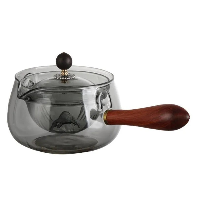 Transparent rotary glass teapot with wooden handle and built-in infuser on countertop