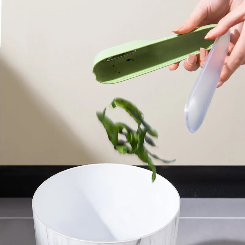 Dark green peeling knife with a storage tube over the blade and a hole in the end of the handle.