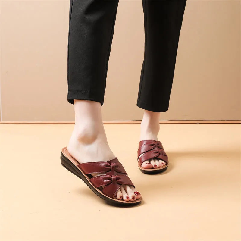 Women's beige cowhide slippers with a soft sole, shown from the side.