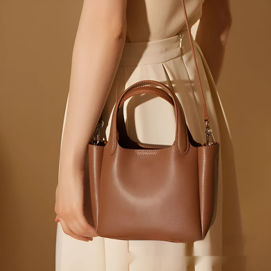 Brown genuine cattlehide leather cross body bucket bag showing sewing thread detail and slit pocket.