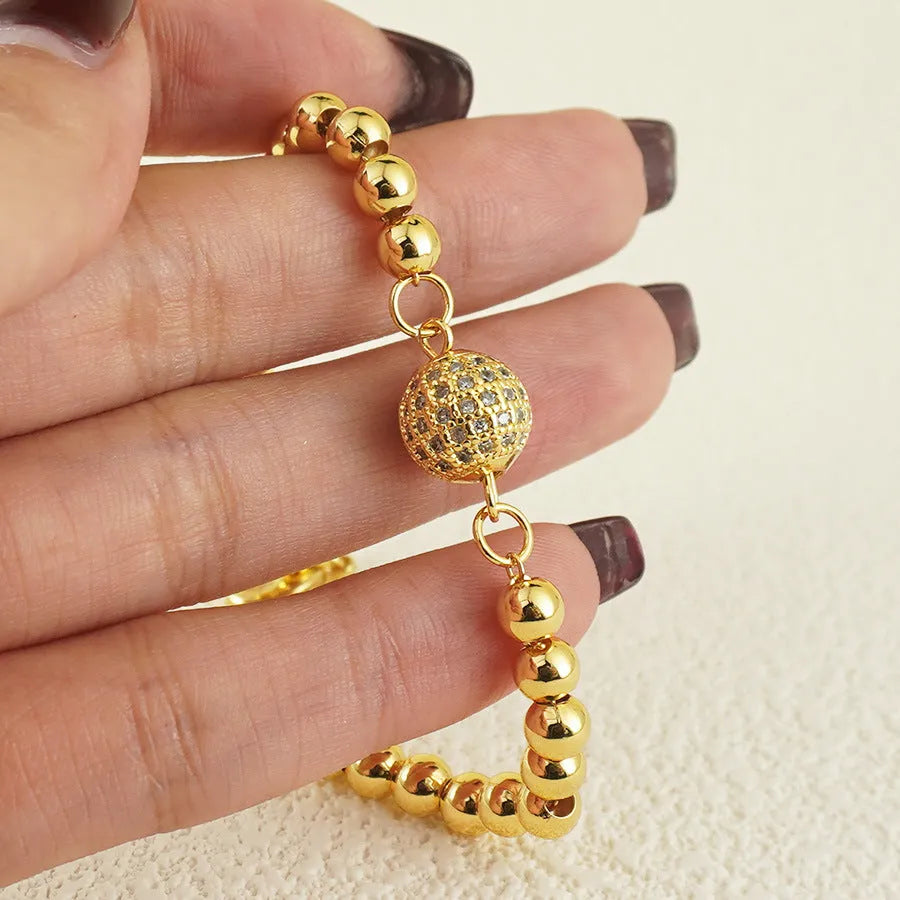 Close-up of a women's copper bracelet with a heart-shaped charm holding a round zircon stone, Arabic style design.