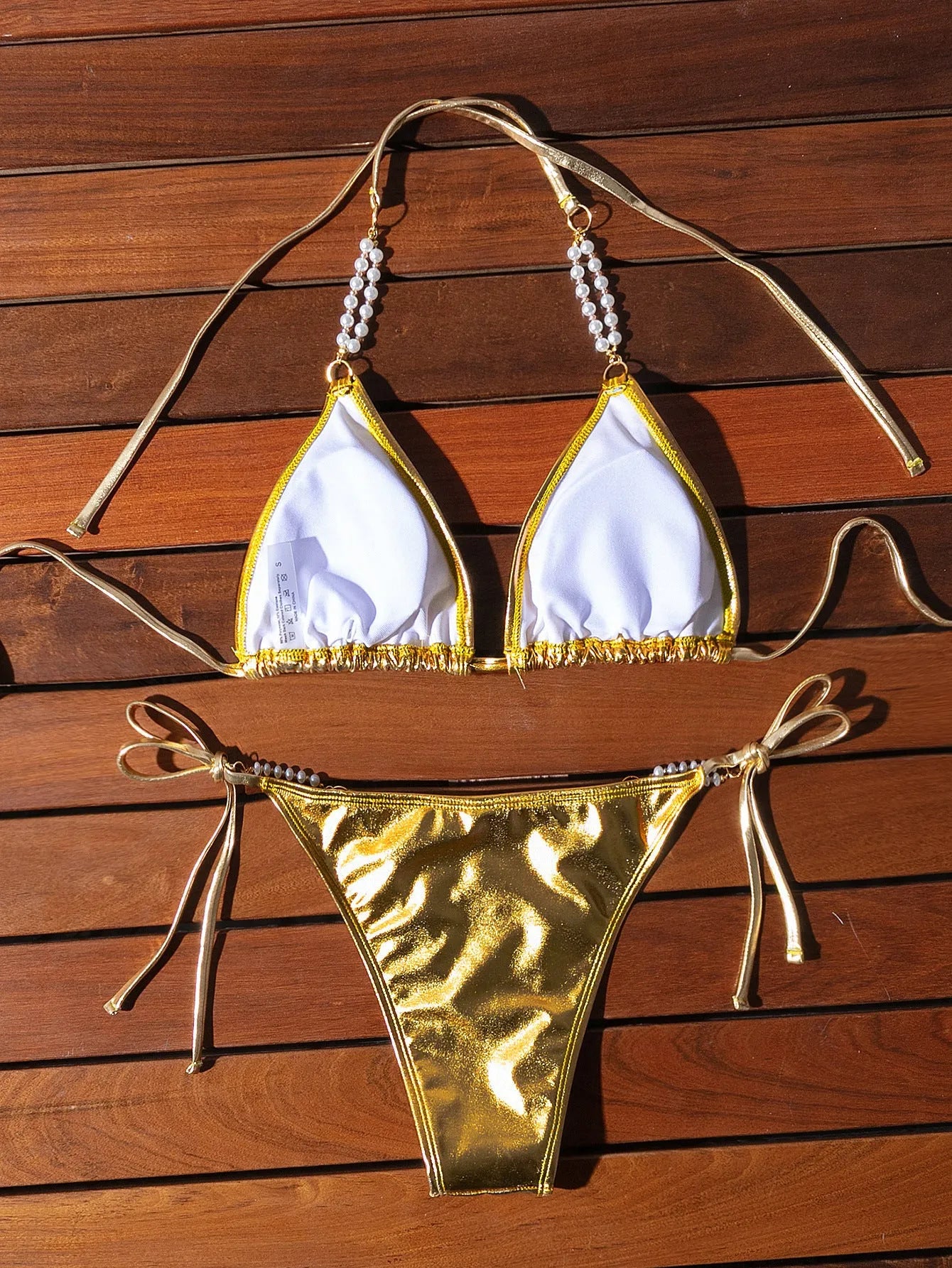 Gold women's bikini swimsuit with halter neck, lace-up back, and pearl chain decoration