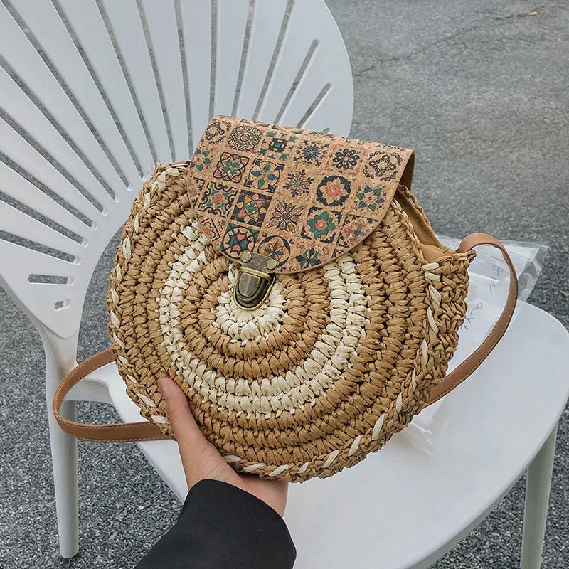 Round straw woven crossbody bag in beige, 25cm diameter, with adjustable shoulder strap, displayed on a neutral background