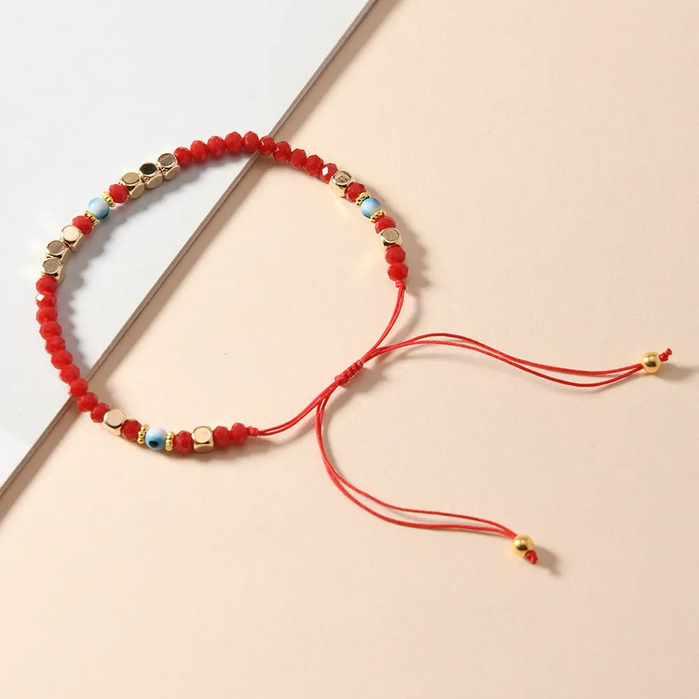 Red hand-woven beaded couple bracelet with artificial crystal eye geometric design on white background