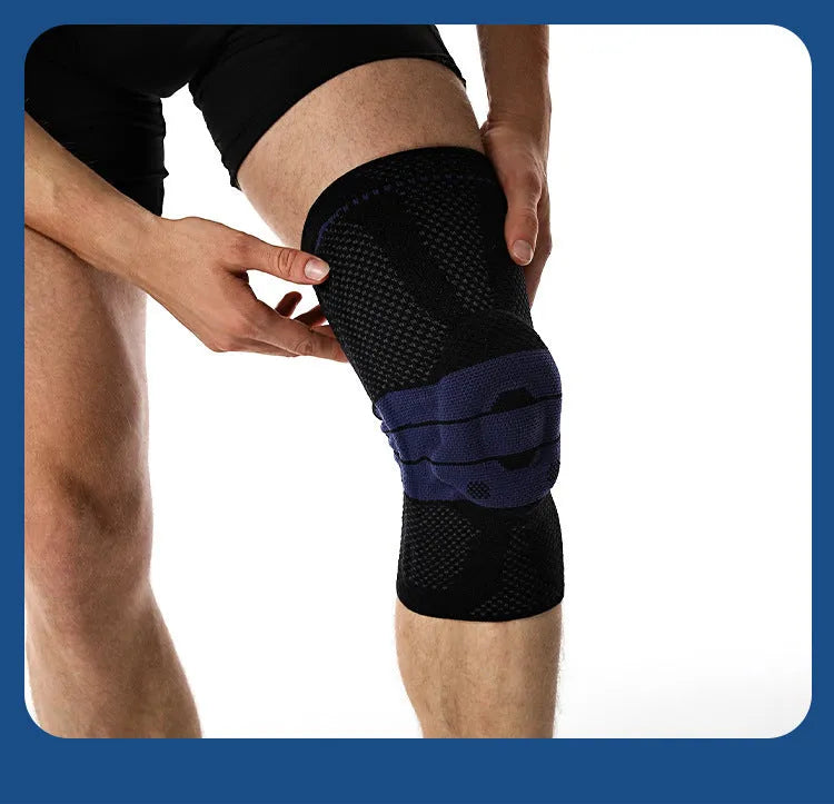 A pair of adult sports knee pads in a black and blue colourway, shown on a knee for scale.