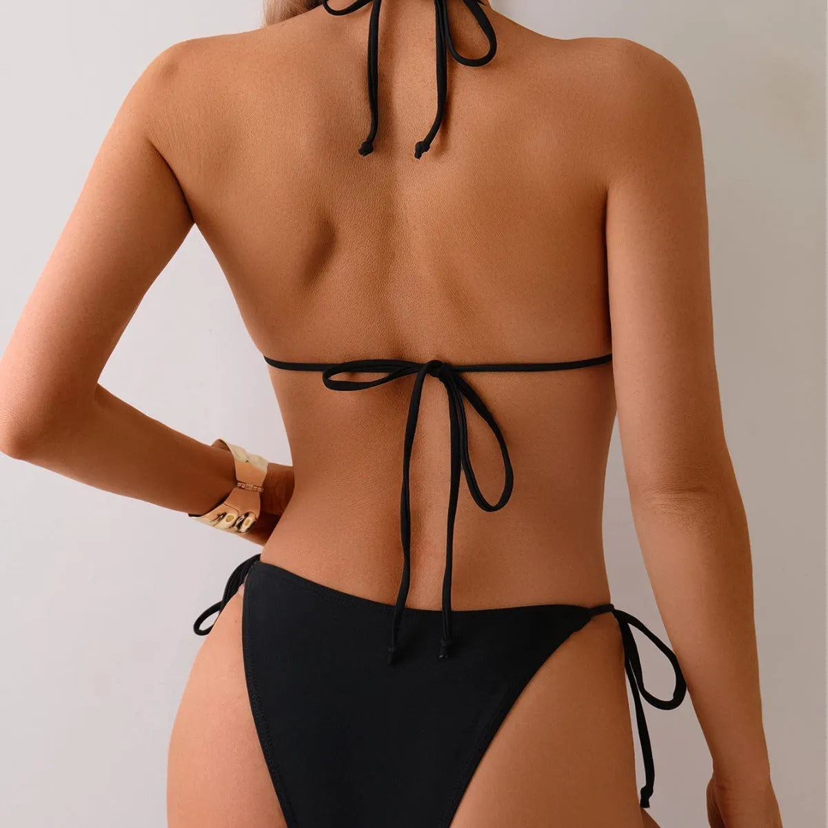 Black women's bikini swimsuit with metal beads on a split skirt.