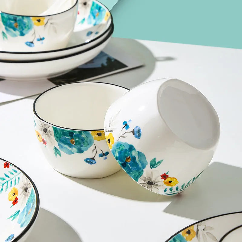 Flower In Ink 22-piece bone china tableware set with floral pattern, bowls, plates, and spoons on a table.
