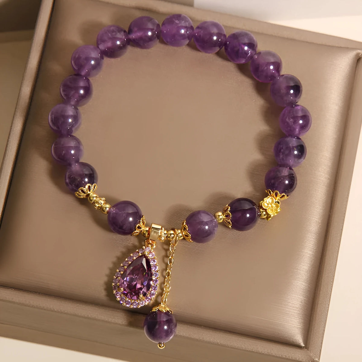 Natural amethyst bracelet with gold-plated inlay and purple droplet pendant on white background