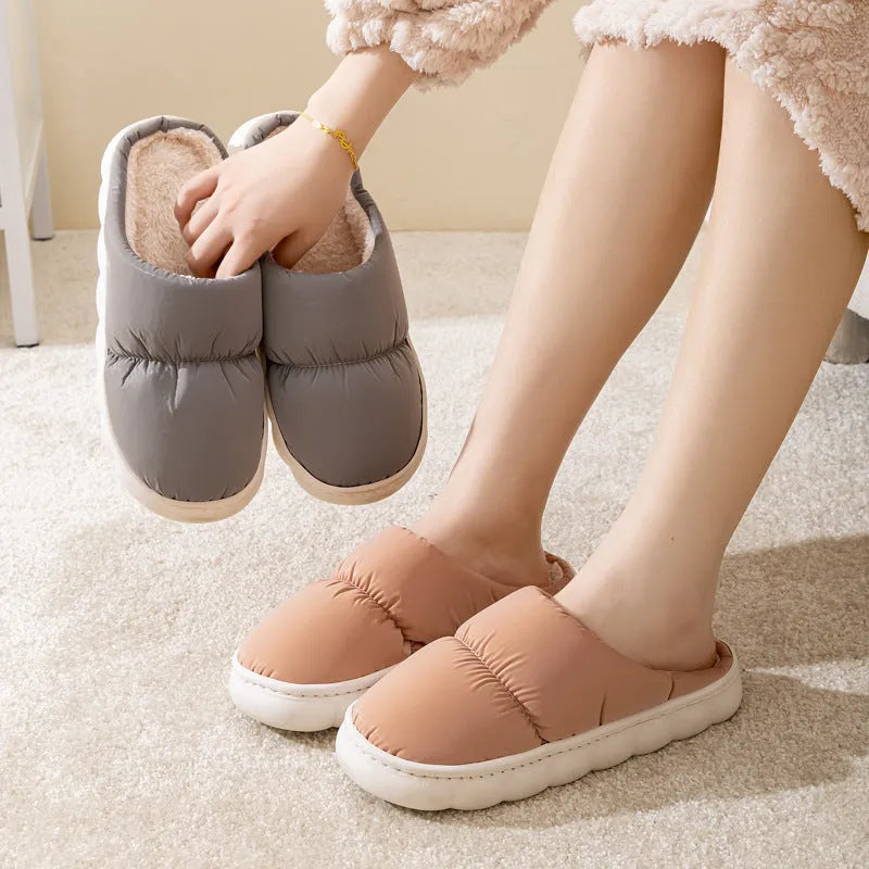 A pair of blue down cotton slippers with a thick sole, artificial leather upper, and plush lining for indoor winter wear.