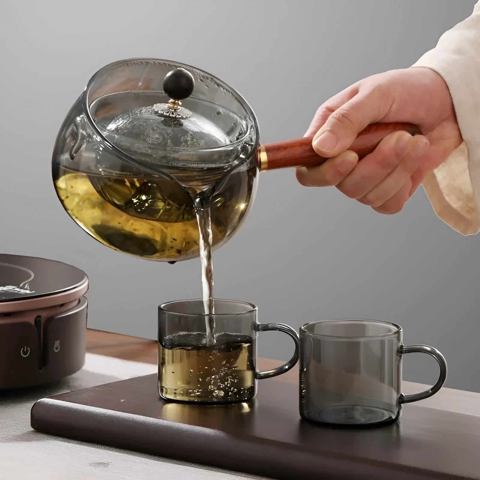 Transparent rotary glass teapot with wooden handle and built-in infuser on countertop