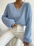 A woman wearing a solid colour long sleeve loose pullover top in a casual setting.
