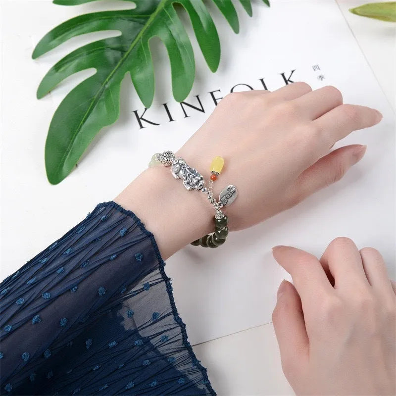 Close-up of a retro women's bracelet with a natural Hetian jade bead and a silver coin pendant on a wrist.