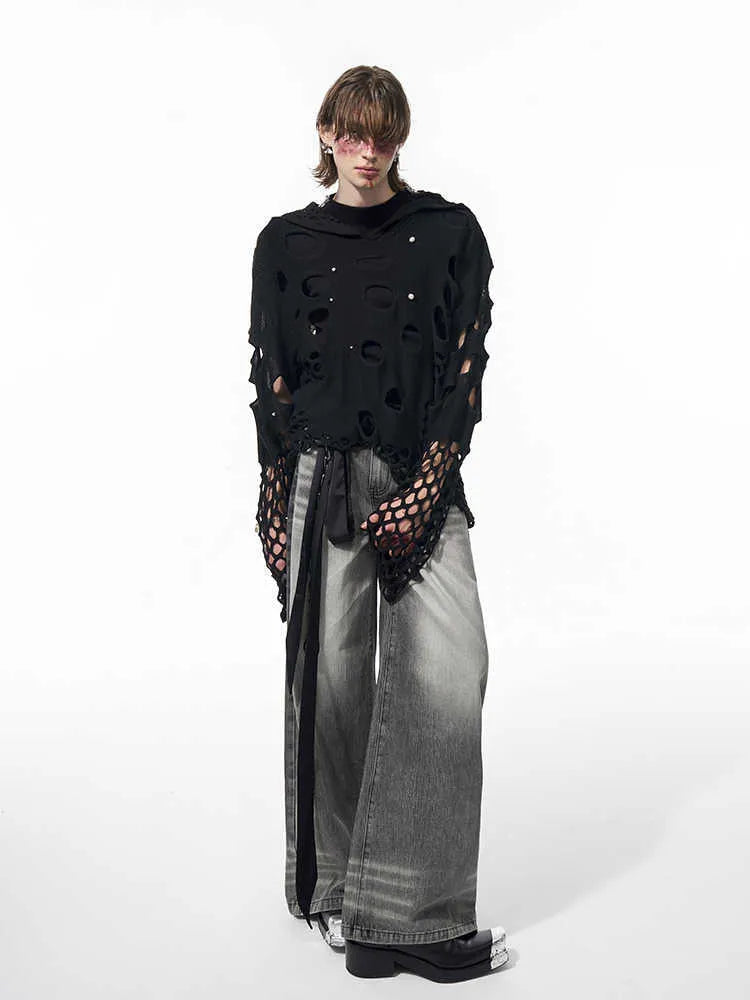 Man wearing a black loose-fit hollow knit hoodie with pearl decorations on the hood.