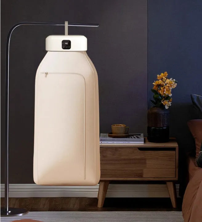 White cylindrical foldable clothes drier with remote control on a table.