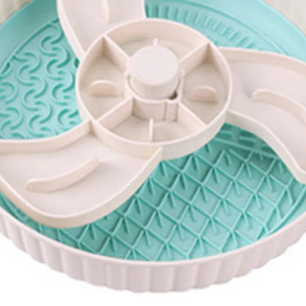 Rotating plastic pet food bowl with a blue silicone slow feed licking mat insert in a windmill pattern.