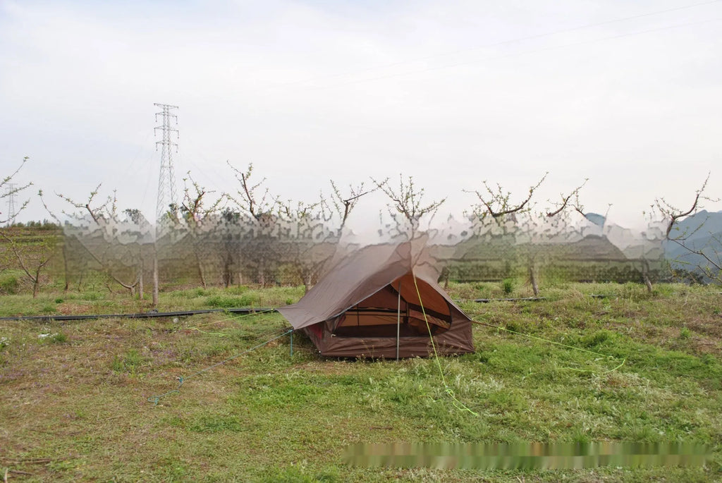 Lightweight brown A-line hiking tent set up with hiking cane supports in outdoor setting