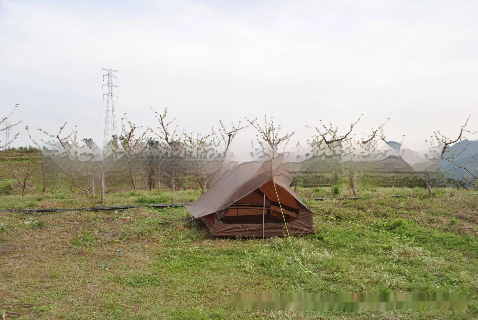 Lightweight brown A-line hiking tent set up with hiking cane supports in outdoor setting