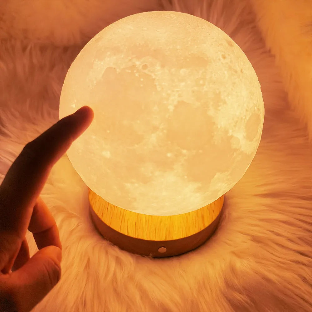 Rotating sleeping moon night lamp on a wooden base with a wire control, showing three colour options.